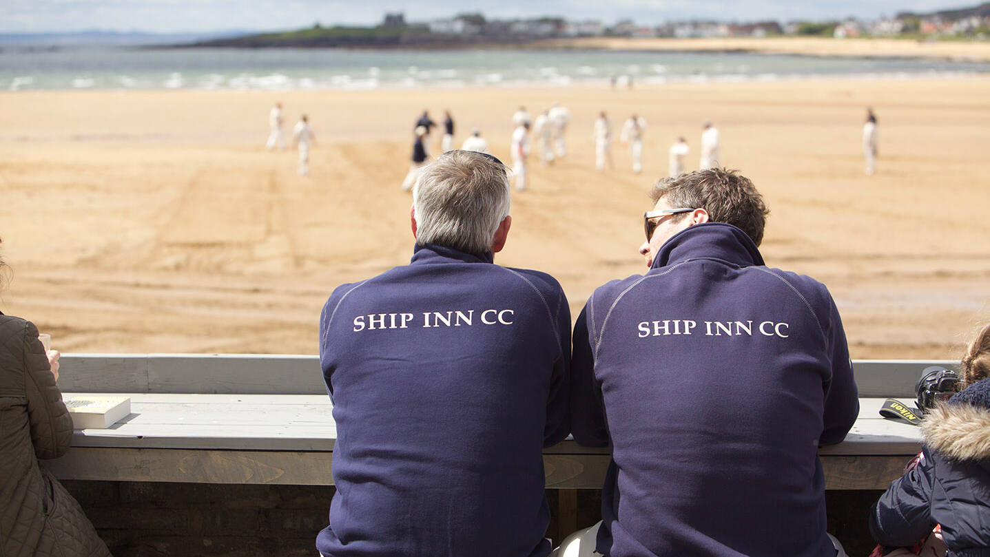 Two people watching cricket on the beach at The Ship Inn, Elie, Fife