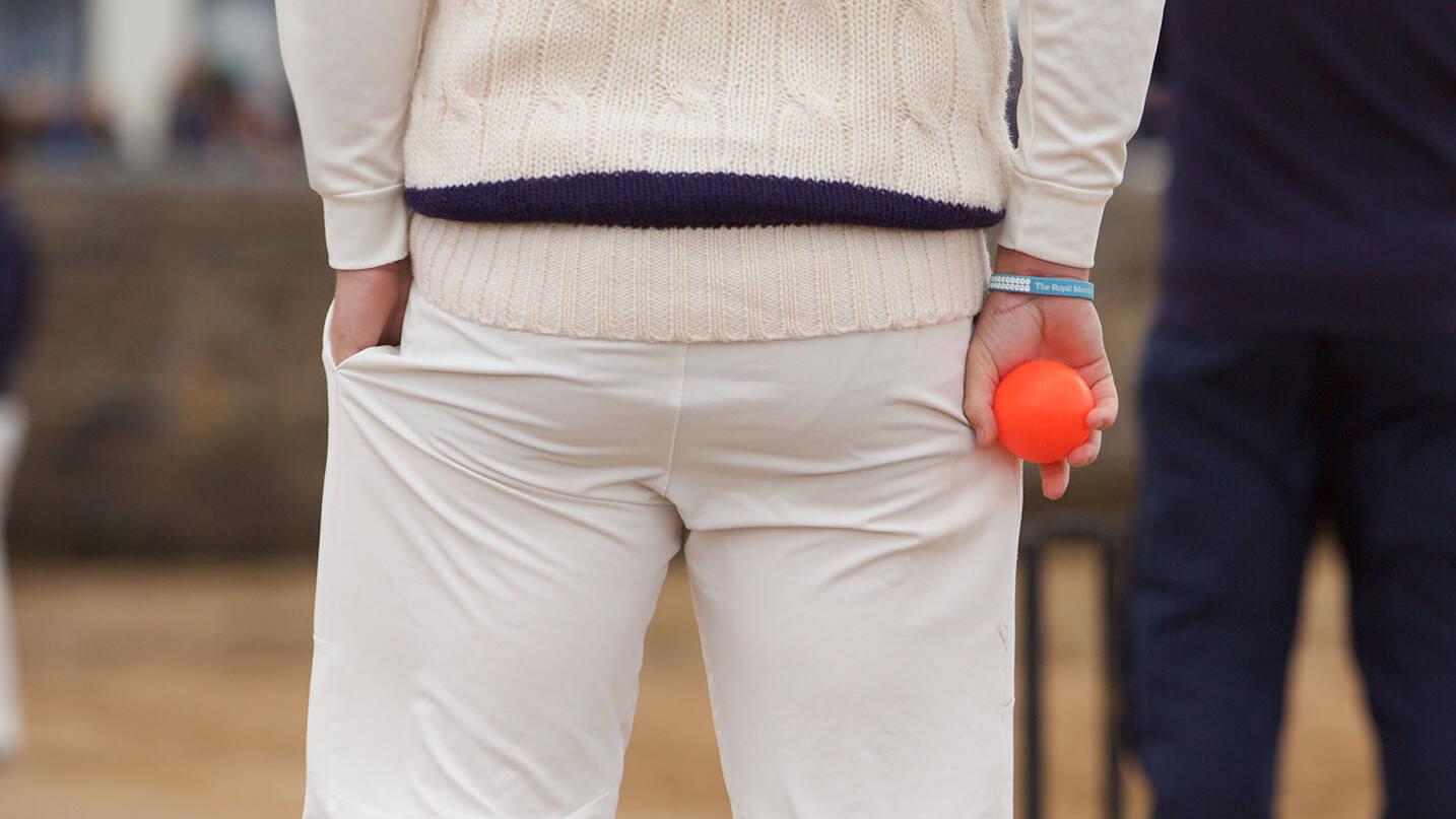 Cricketer holding orange cricket ball outside The Ship Inn, Elie, Fife